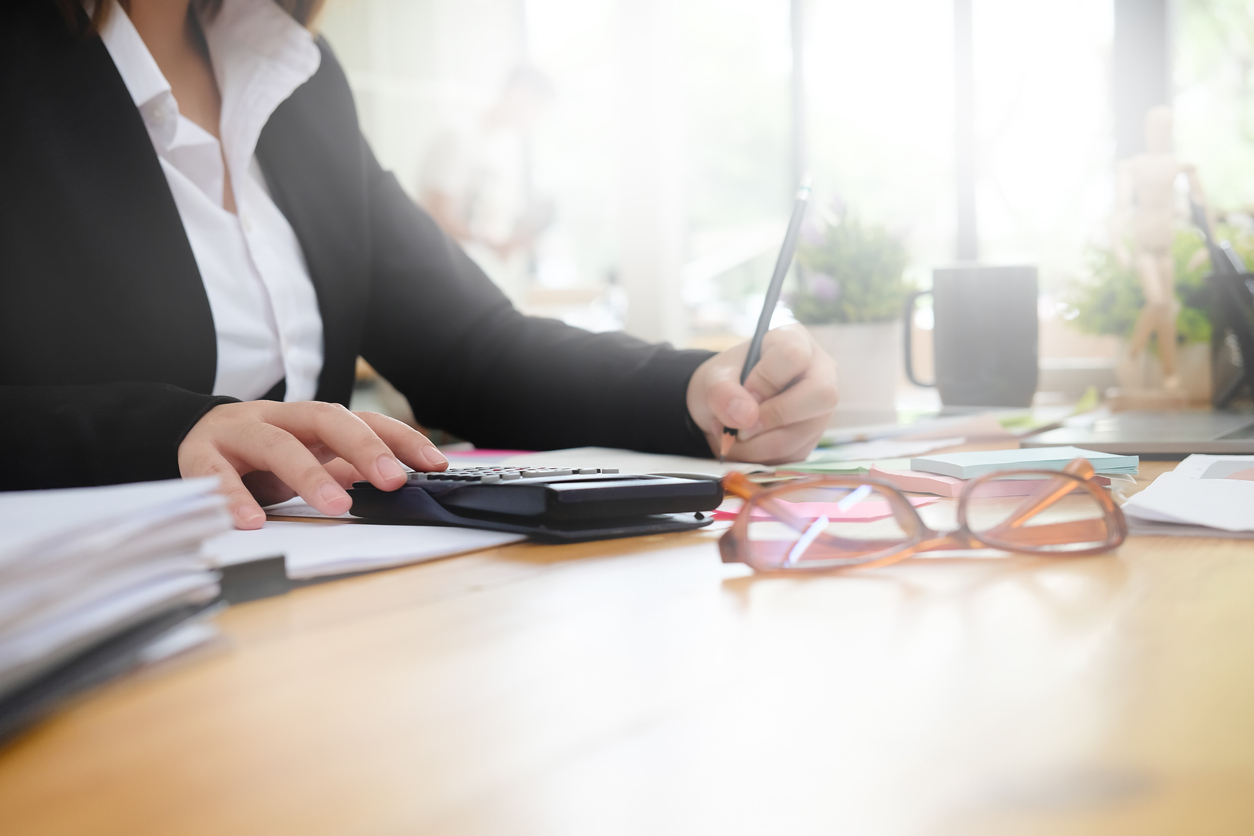 Businesswoman calculate financial data on workplace with morning light.